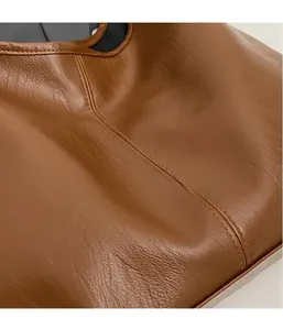 Close-up of caramel brown tote bag showing soft pebbled leather texture and stitching