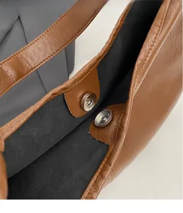 Close-up of caramel brown faux leather tote with round metal magnetic snap closure