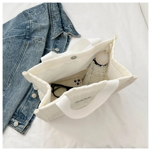 Interior detail of white quilted tote bag showing large capacity for umbrella and phone