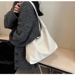 Detail of white large PU leather tote bag styled with a grey knitted cardigan for a chic look