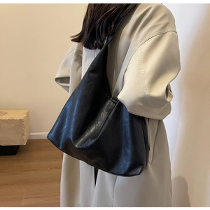 Detail of the soft black leather texture and fine stitching on a large tote shoulder bag