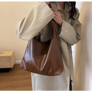Brown polished leather tote bag shown on model with minimalist indoor background scene
