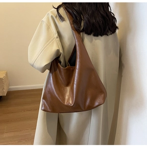 Detail of a large vintage brown tote bag in matte PU leather shown on a shoulder