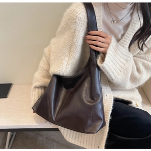 Macro detail of deep brown hobo bag showing soft leather texture and shoulder strap
