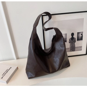 Close-up of dark brown leather tote bag with soft texture and minimalist hobo style design