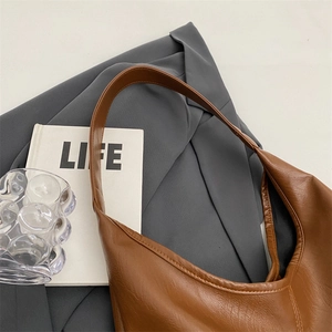 Close-up of caramel hobo bag showing pebbled leather texture and minimalist design