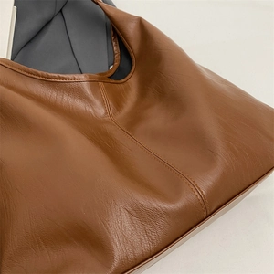 Macro view of dark brown PU leather tote bag showing detailed texture and stitching