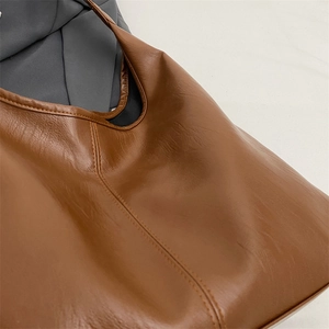 Detailed macro view showing brown PU leather texture and vertical stitching on tote bag
