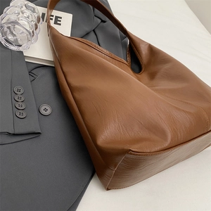 Detailed texture of brown PU leather hobo bag on a dark suit with a modern office aesthetic