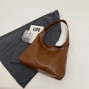 Detailed view of brown faux leather tote bag with stitching on a minimalist setting