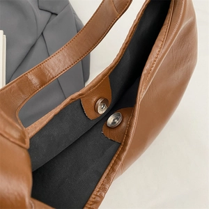 Detail view of large tote bag interior with dual silver magnetic buckles and lining