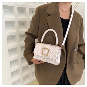 Quilted cream crossbody bag with gold buckle shown on professional fashion model