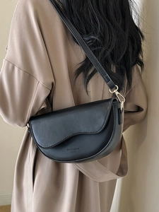 Matte black leather saddle bag with wave edge and wide shoulder strap on model