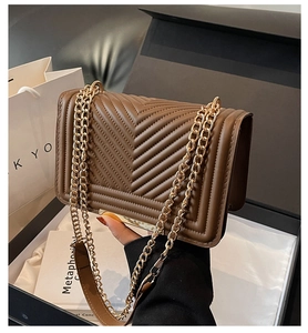 Detail of dark brown quilted crossbody bag with gold chain strap and luxury packaging