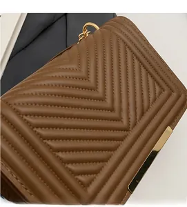 Detail of brown V-quilted faux leather crossbody bag with gold hardware and metal clasp