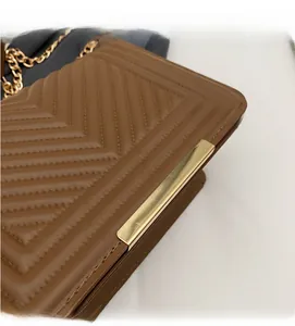 Close-up of brown faux leather bag with V-quilt stitching and gold metal bar detail
