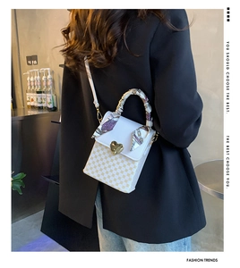Close-up of checkered small crossbody bag with gold heart lock and silk ribbon handle