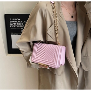 Detail showing the pink V-quilted faux leather bag with elegant gold chain strap and lock