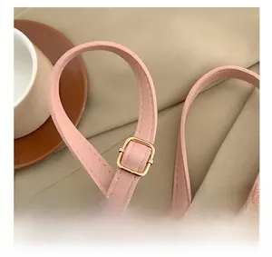 Detail of adjustable pink leather strap with a polished golden buckle and stitching