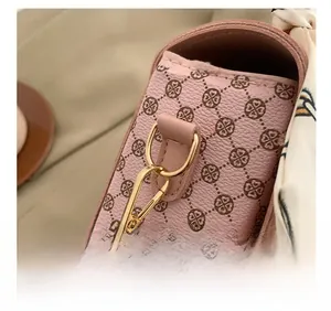 Close-up of pink plaid leather handbag featuring golden hardware and decorative silk ribbon