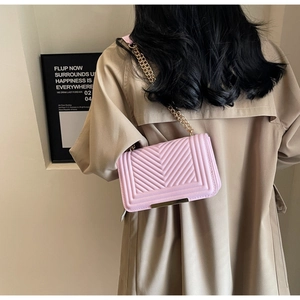 Model wearing a pink chevron quilted chain crossbody bag against a minimalist wall