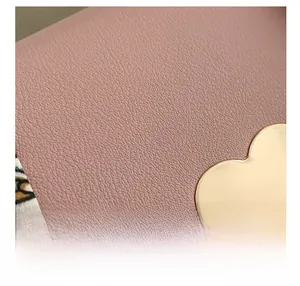 Macro detail of pink pebble texture fabric with a gold heart-shaped metal accent and stitching