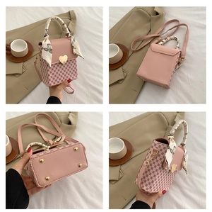 Detail view of pink plaid handbag with heart lock, silk scarf handle and bottom rivets