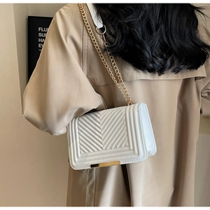 Close-up of white V-quilted faux leather bag with gold chain strap and metal trim