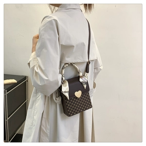 Detail view of mini plaid bag with golden heart clasp and decorative scarf handle