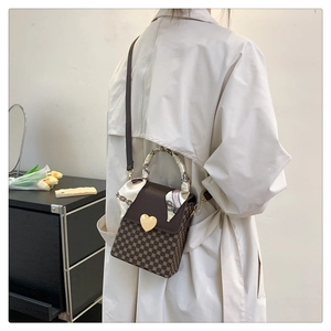 Classic checkered crossbody bag with golden heart lock and silk scarf on a trench coat
