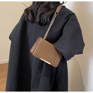 Close-up of brown PU leather shoulder bag with V-shaped quilting and gold chain strap