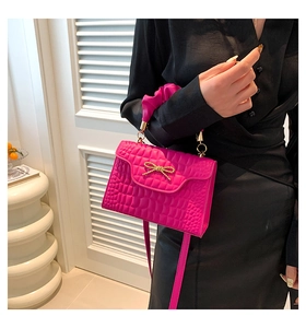 Détail du sac carré rose fuchsia aspect croco avec nœud doré et poignée froncée