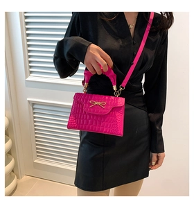Détail du sac à main rose fuchsia effet crocodile avec anse froncée et nœud doré