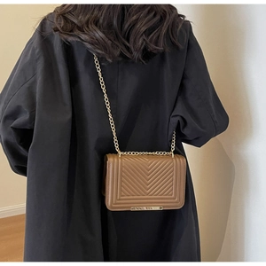 Rear view of brown quilted chain bag with chevron stitching on female model