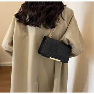 Detailed view of quilted black leather shoulder bag with gold metal trim and chain strap