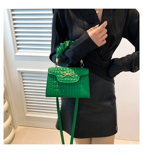 Détail du sac à main vert vif embossé croco avec nœud doré et poignée froissée