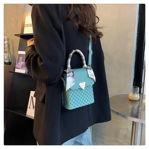 Detail of light blue plaid crossbody bag with gold heart buckle and silk scarf handle