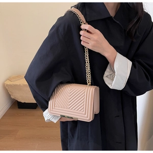 Detail of beige quilted leather chain bag with V-shaped stitching and gold hardware