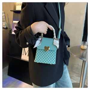 Mint green crossbody handbag with heart lock and silk scarf handle on black blazer