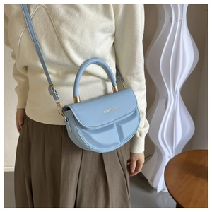 Modelo con bolso de montura de media luna azul claro con asa redonda y letras doradas