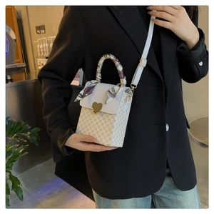 Detail of plaid crossbody bag with heart buckle and silk ribbon wrapped handle