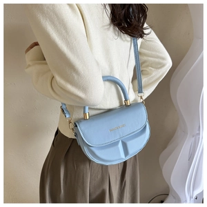 Detalle del bolso semicircular azul claro de PU con relieve texturizado y herrajes dorados
