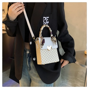 Crossbody plaid handbag with heart lock and silk scarf handle on black blazer model