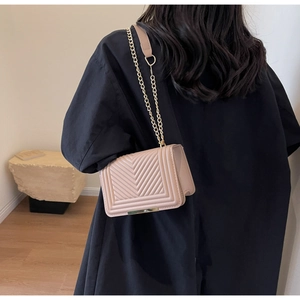 Pink quilted crossbody bag with V-shaped stitching and golden chain shoulder strap
