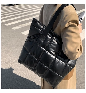 Sac cabas noir matelassé en tissu rembourré porté par un mannequin en manteau de laine