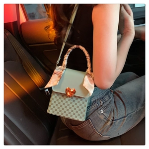 Detail of mint green flap handbag with heart lock and silk ribbon on handle