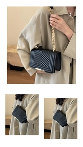 Detail view of black V-quilted small square bag with light gold chain shoulder strap