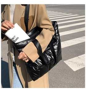 Sac fourre-tout noir matelassé chic en tissu brillant porté par un mannequin en manteau