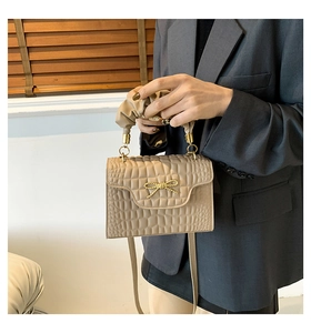 Détail du petit sac carré à motif crocodile avec nœud doré et poignée plissée