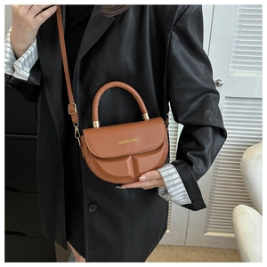 Bolso bandolera marrón de media luna con diseño texturizado sobre chaqueta de cuero